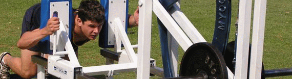 The ScrumTruk strength-increasing machine is used for development of the pushing muscles employed in the rugby scrum. Note that the body position is virtually identical to that adopted in both the scrum itself and when using the 8-man scrum machine. The player has intuitively adopted a natural exercising position with straight line loading on the lumbar region.